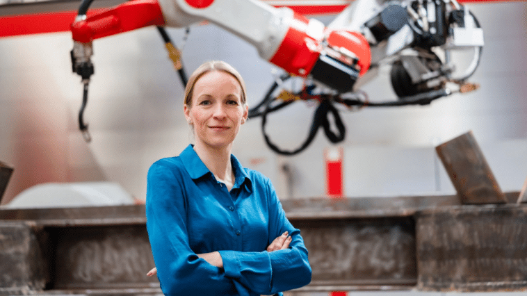 Une femme entrepreneur derrière une main robotique.