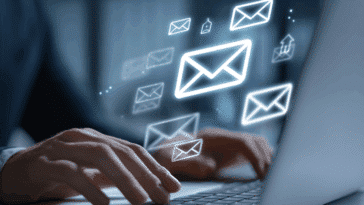 Une personne travaillant sur un ordinateur avec un gros symbole email sur l’écran, montrant des enveloppes fermées.