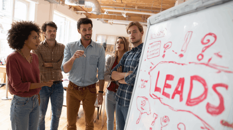 Réunion d'une équipe marketing autour d'un tableau digital affichant “LEADS ?”, illustrant la réflexion stratégique en prospection digitale.
