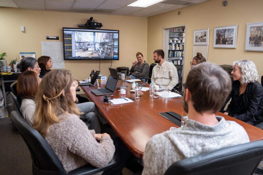 Réunion d’équipe associative dans une salle modeste, avec projection d’un pipeline illustrant les adhésions, dons et bénévolat, pour une gestion efficace.