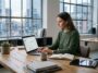 Une femme utilise Frase AI sur son ordinateur portable pour optimiser le contenu SEO dans son bureau moderne au crépuscule.