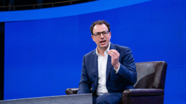 Dario Amodei sur scène pour illustrer le projet d'Anthropic de fabriquer ses propres puces IA