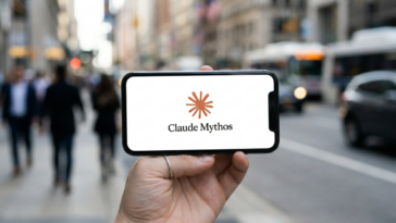 Main tenant un smartphone affichant le logo Claude Mythos sur fond de rue urbaine floue.